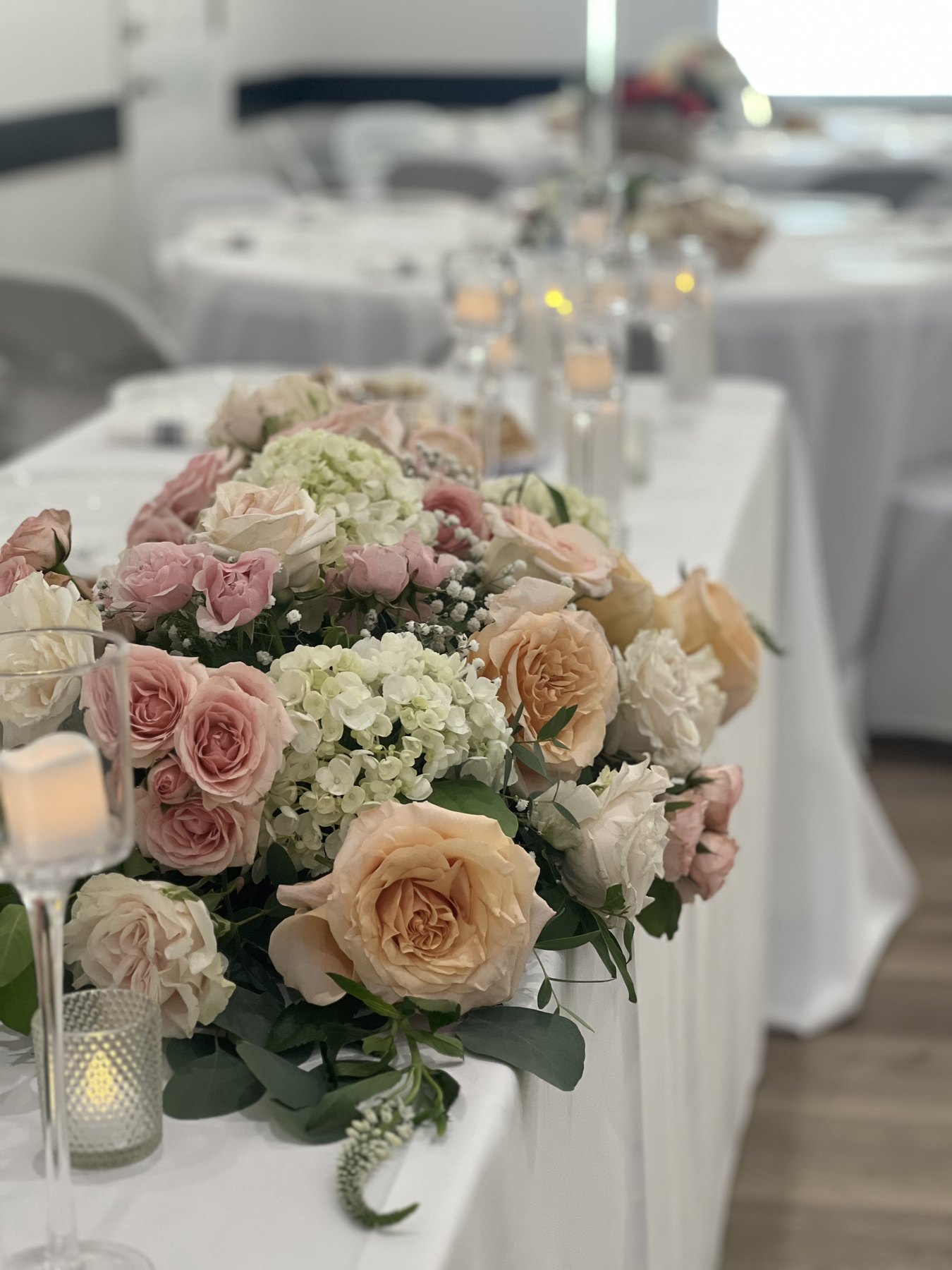 Pink and cream centerpiece with candles on a white table