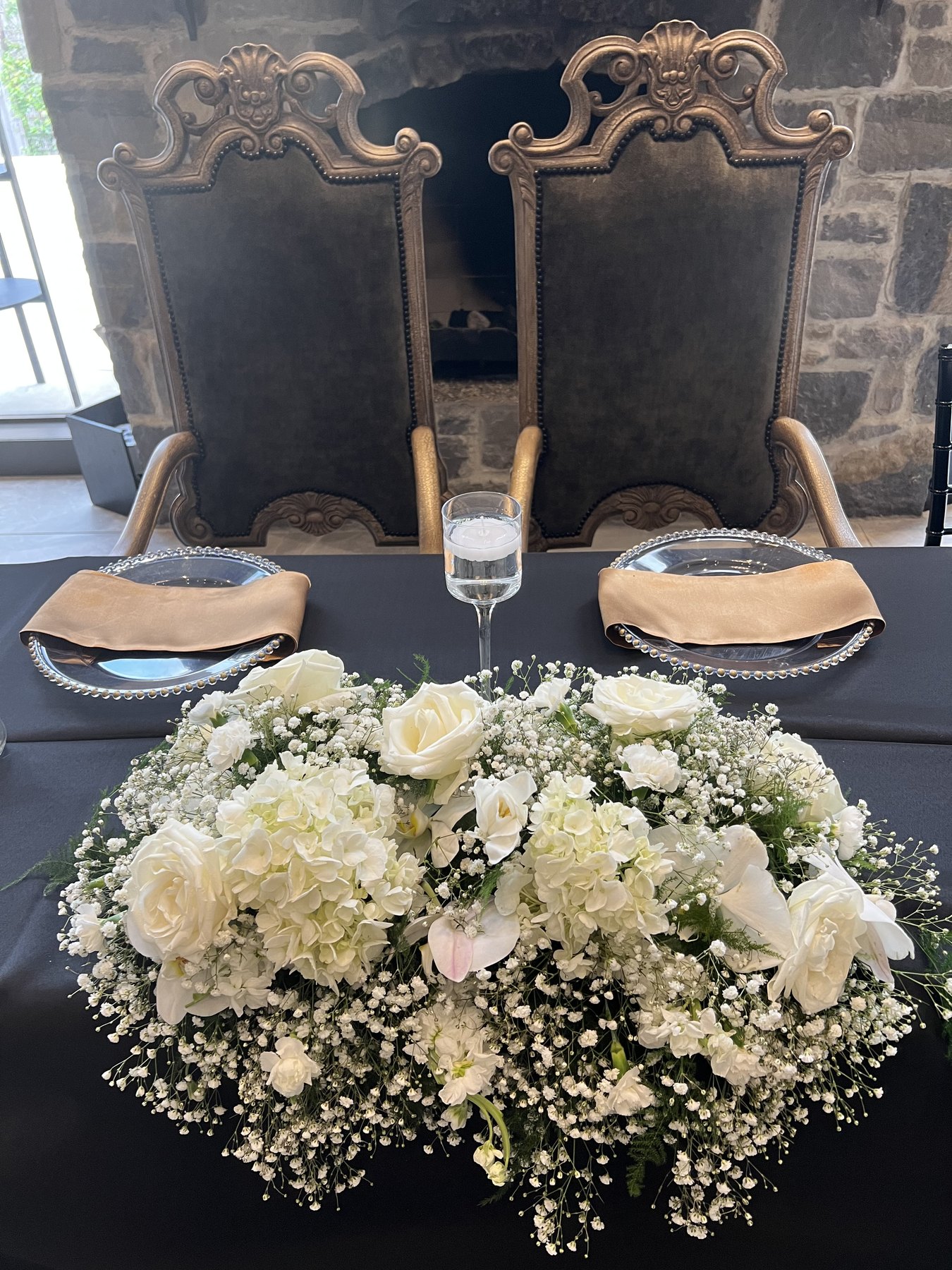 Large floral centerpiece with ornate chairs and black linens