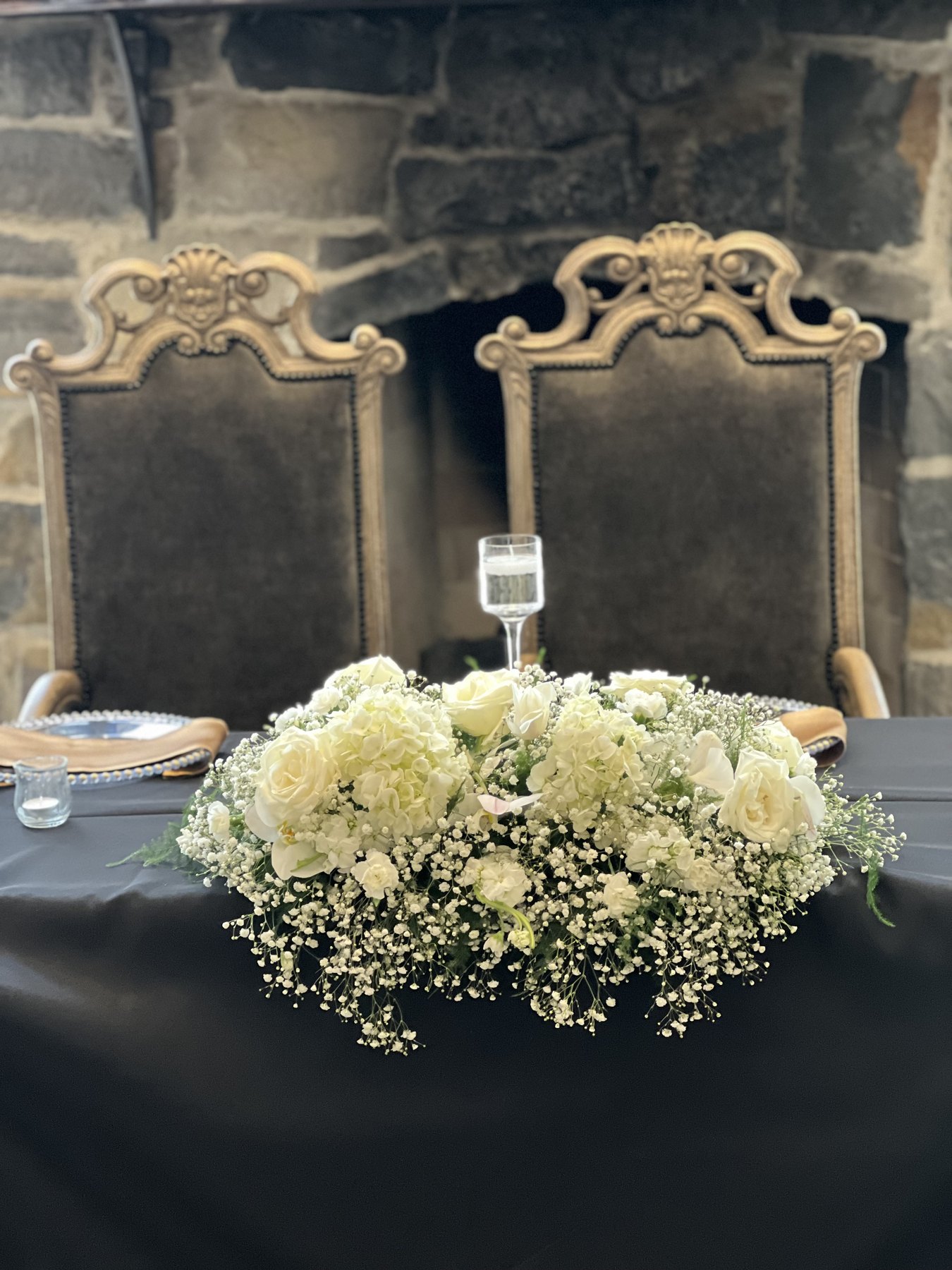 White floral centerpiece on a dark table with place settings