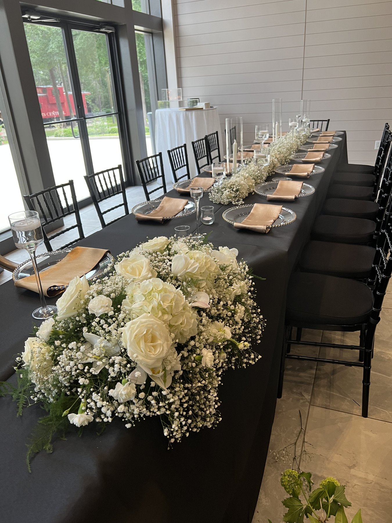 Long table with white flowers, black chairs, and glassware