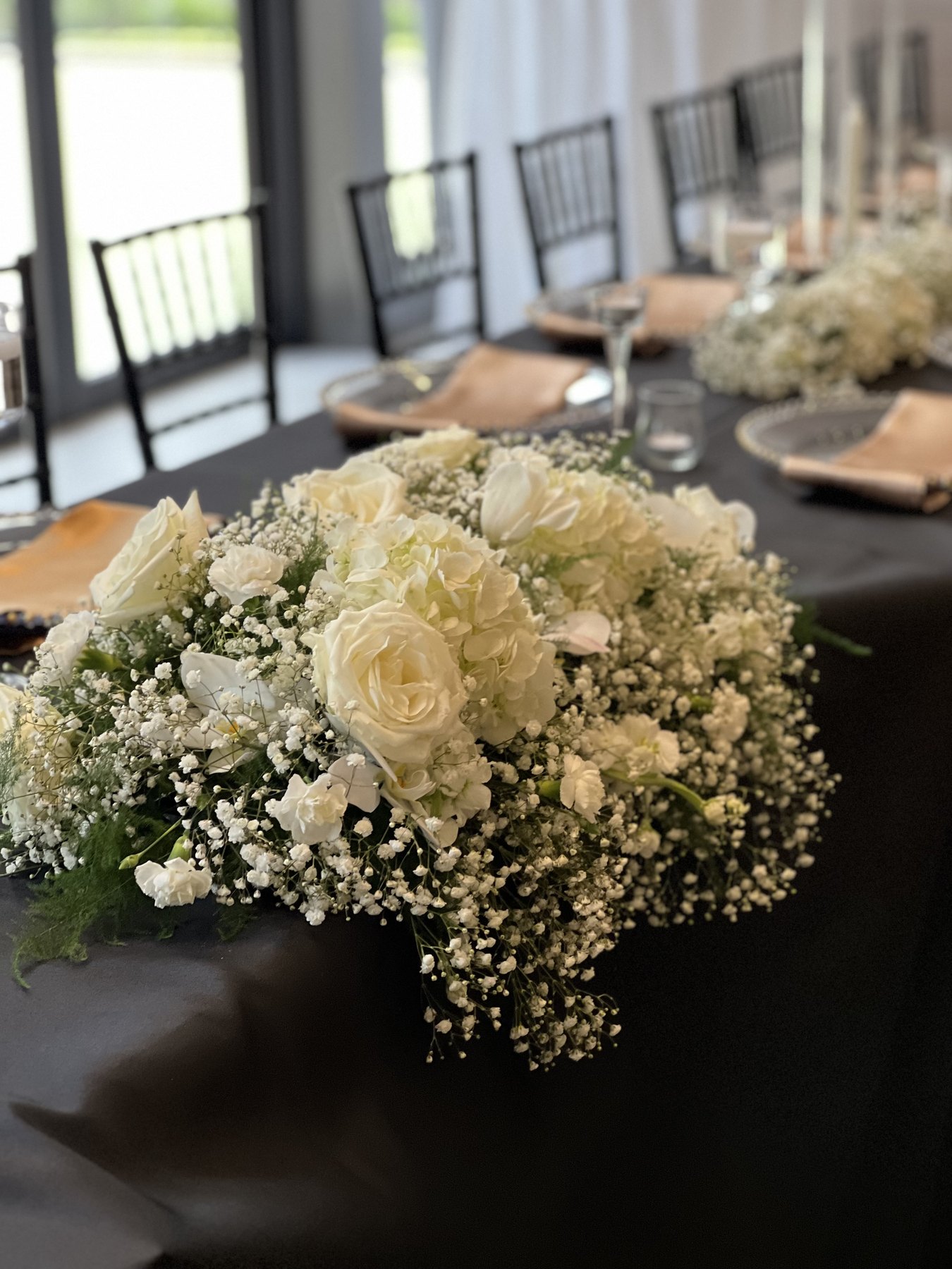 White floral arrangement with baby breath on black linen