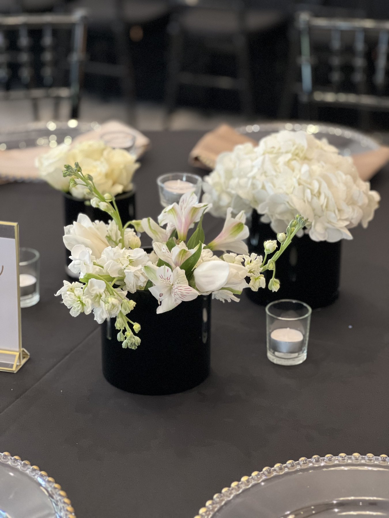 White floral centerpiece with candles on black table linen