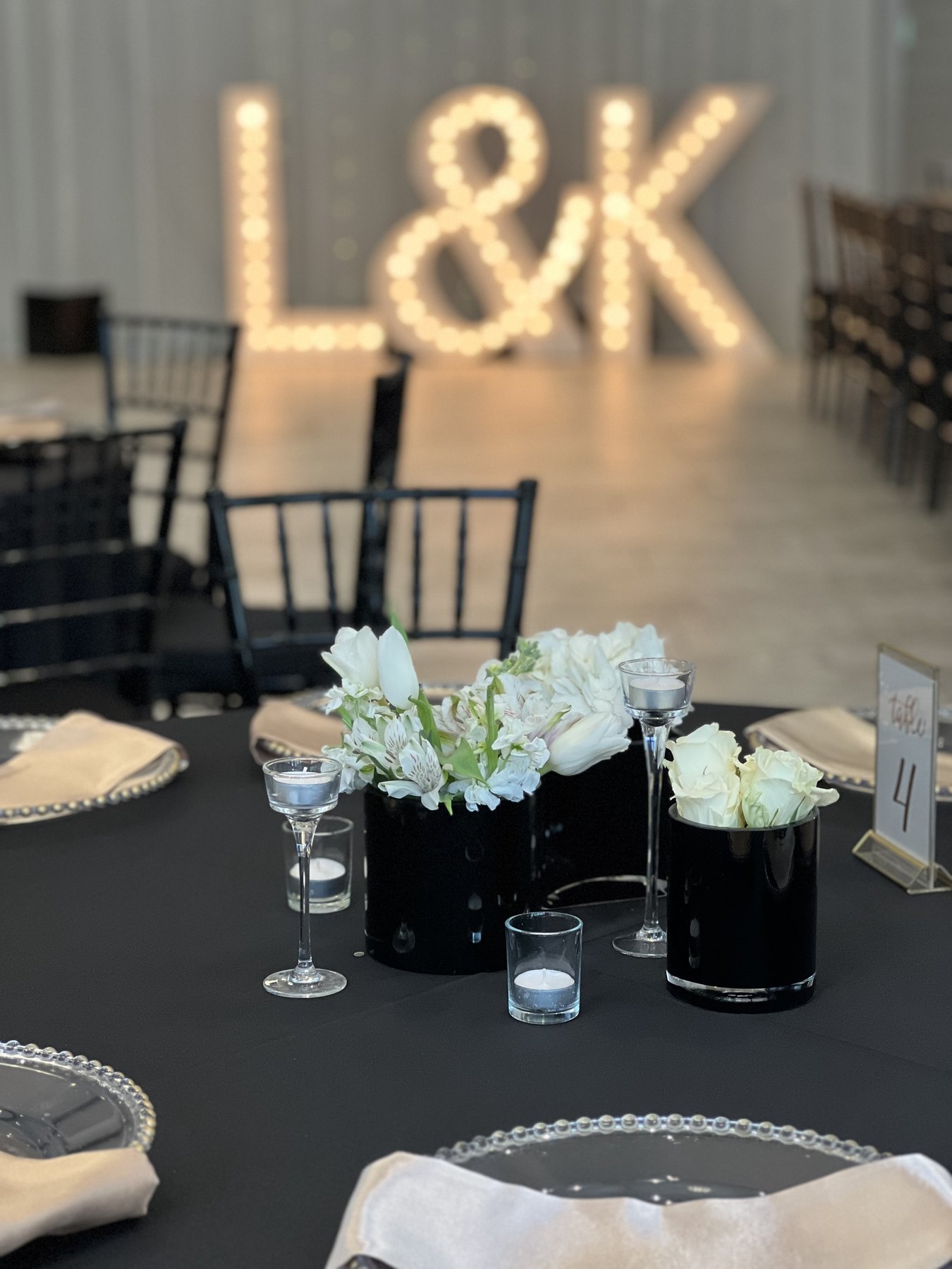 Black table with illuminated initials and white floral centerpiece