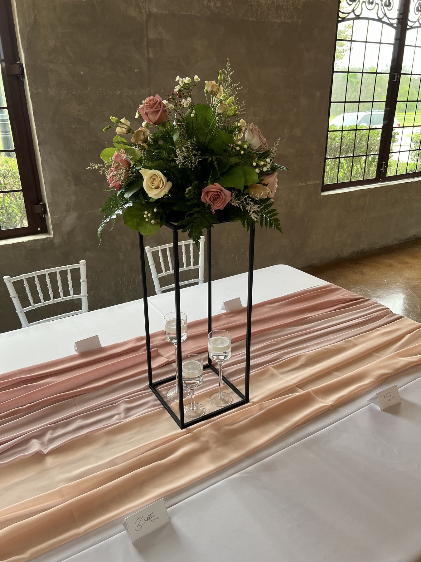 Hanging floral arrangement near event draping and windows